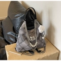 Close-up of grey quilted bag with silver bow detail and pearl chain tassel on a stone - With Charm / Dark Brown