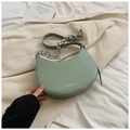 Détail du sac selle vert clair avec chaîne en métal et logo FASHION élégant - Vert