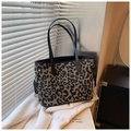 Leopard print tote bag with black leather handles and metal hardware on soft window light - Black