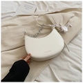 Detailed view of a white crescent saddle bag with silver chain and silk scarf on a blazer - White