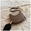 Gros plan d'un sac selle marron avec chaîne argentée et foulard en soie sur blazer beige - Café