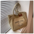 Detail of khaki canvas tote bag with front pocket and embossed leather label logo - Khaki