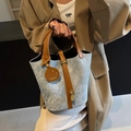 Light blue denim bucket bag with brown leather handles and decorative smile charm - Blue