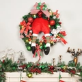 Corona de Navidad iluminada con piernas de elfo y calcetines a rayas en pared - Estilo Patas de Elfo