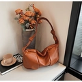Close-up of brown pleated leather shoulder bag with knot strap detail and metal zipper - Caramel