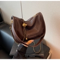 Détail du sac demi-lune en cuir marron foncé avec breloque boule dorée et bandoulière chaîne - café