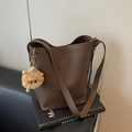 Bolso cubo marrón con grano litchi, correa y colgante de peluche sobre libro negro - Café (Con Colgante)