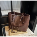Detalle del bolso tote de cuero encerado marrón oscuro con sutil logotipo dorado - café