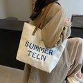 Cream canvas tote bag with blue 3D embroidery and brown leather straps worn by a model - Off-white