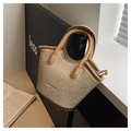 Detailansicht der geflochtenen Eimertasche mit braunem Lederbesatz und silbernen Metallteilen - Gewebte Textur / Khaki