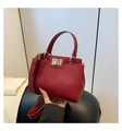 Close-up of wine red litchi texture leather bag with golden twist lock and top handle - Red