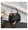 Detailed shot of a black pebbled leather handbag with a gold square clasp and round handle - Black