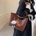 Brown vintage tote bag with embossed pattern and cloud plush charm on a model's shoulder - Brown with Pendant