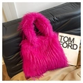 Vue détaillée du sac cabas en peluche rose vif posé sur un canapé en cuir noir élégant - Rose rouge
