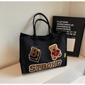 Dettaglio borsa tote in tela nera con ricamo orsetto e toppa con lettera B ricamata - Nero