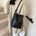 Chic black leather bucket bag with geometric patchwork and knotted shoulder strap - Black