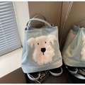 Détail d'un sac cabas bleu clair avec un chiot en peluche blanche sous lumière naturelle - Bleu