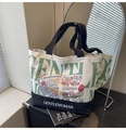 Dettaglio della borsa tote in tela con scritta Gentle verde e tracolla nera - Verde