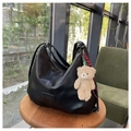Detail of black pebbled PU leather tote bag with a cute beige teddy bear charm on wood stool - Black With Pendant