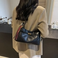 Black leather crossbody bag with gold buckle and woven rope detail worn with khaki blazer - Black
