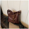 Detailansicht der weinroten Leder-Eimertasche mit goldener Kette auf schwarzer Bank - Ancorra Rot