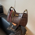 Vintage brown leather crossbody bag with gold lock and red-green woven strap detail - Coffee