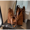 Détail d'un sac cabas en daim marron avec un nœud décoratif et des anneaux en métal chic - Marron