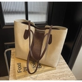 Dettaglio borsa tote bicolore con texture vintage in ecopelle su un libro minimalista - Bianco Sporco