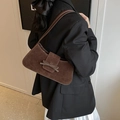 Brown suede shoulder bag with bow detail worn by a model in a modern fashion style - Brown