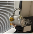 Detailed view of silver metallic bag with embossed logo and orange plush monster charm - Silver