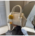 Detail of cream white leather bag with metal clasp and yellow plush charm accessory - Off-white