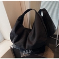 Close-up of black matte suede tote bag showing soft texture and wide shoulder strap detail - Black