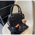 Chic black vintage matte handbag with embossed logo and plush bear charm on white chair - Dark Brown