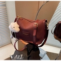Detalle del bolso de cuero burdeos con hebillas doradas y colgante de nube blanca suave - Burdeos