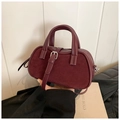 Deep burgundy leather Boston bag with dual handles and adjustable strap in lifestyle setting - Burgundy