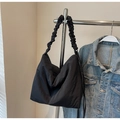 Detail of black tote bag with ruched shoulder strap hanging on a silver metal rack - Black