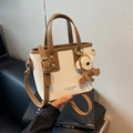 Bolso mini tote en color beige y marrón con correa ajustable y colgante de oso - Blanco y marrón con colgante