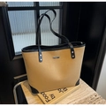 Detalle del bolso tote de ante caqui con bordes de cuero negro y logo de metal plateado - Caqui