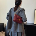 Burgunderrote gesteppte Wildledertasche mit Goldkette an der Schulter des Models - Rot
