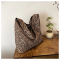 Dettaglio di una borsa tote in tela con stampa leopardata su un tavolo in legno - Cachi