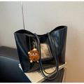 Detail of black faux leather tote bag with plush monster charm on business books - With Charm / Black