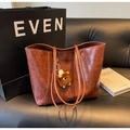 Detailed view of deep brown vintage tote bag with plush monster charm on leather sofa - With Charm / Brown
