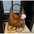 Detailansicht der karamellbraunen Hobo-Tasche mit M-Logo, Kette und Wolkenanhänger - Braun mit Anhänger