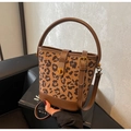 Detailaufnahme der Leoparden-Beuteltasche mit Drehverschluss aus Gold und Ledergriff - Kaffeebraun