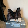 Elegante borsa tote leopardata con tracolla in pelle nera su una valigia - Marrone