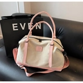 Close-up of beige canvas travel bag with pink leather handles and detachable shoulder strap - Pink