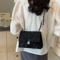 Schicke schwarze Stepptasche mit silberner Kette in einer Lifestyle-Umgebung gezeigt - Schwarz