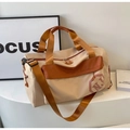 Détail du sac de voyage beige avec sangles orange et logo NJ sur un présentoir moderne - Khaki