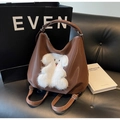 Detail of dark brown tote bag with white plush cartoon patch on a fashion magazine - Puppy Coffee