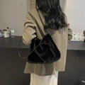 Furry black faux fur shoulder bag for winter fashion, shown styled on a model's shoulder - Black